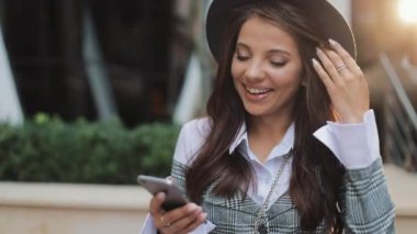 Kentsel Caddesi üzerinde duran ve smartphone kullanarak profesyonel genç iş kadını. İyi haber okumak güzel kadın. Konsept: yeni iş, iletişim, iyi haber