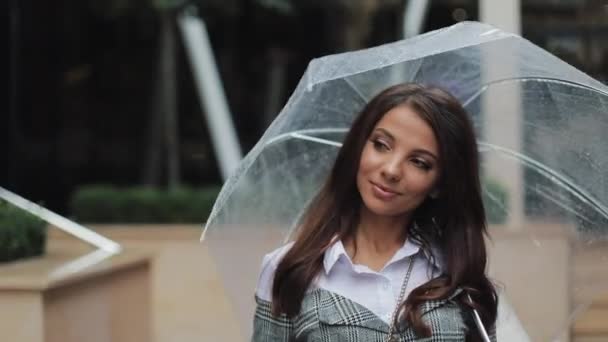 Чарівна молода бізнес-леді в капелюсі йде з парасолькою по вулиці старого міста. Красива дівчина щаслива, вона посміхається. Дощова погода — стокове відео