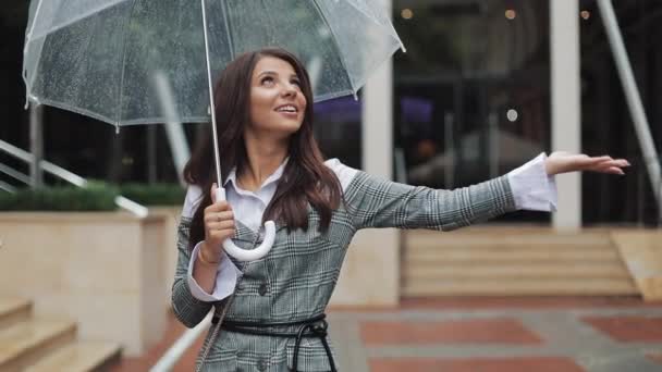 Mujer de negocios guapo joven mirando hacia el cielo y levantando la mano para comprobar si la lluvia se detiene. Ella sonrió y cerró su paraguas disfrutando del final de la lluvia — Vídeo de stock