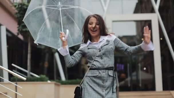 快乐的年轻女商人用伞跳舞 检查雨是否停了 她微笑着 在商务中心的背景下享受着雨的尽头 — 图库视频影像