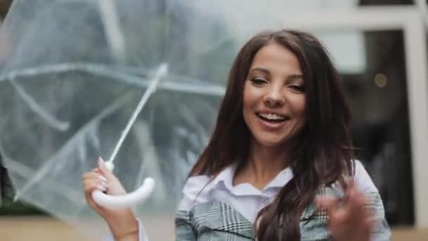 Feliz joven mujer de negocios bailando con paraguas comprobando si la lluvia se detiene. Ella sonriendo y disfrutando del final de la lluvia en el fondo del centro de negocios — Vídeos de Stock