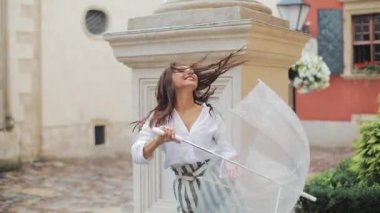 Dans ve having fun şemsiye ile eski şehir sokakta mutlu genç kadın. Güzel firl seyir ve küçük yağmur düşen kameraya poz