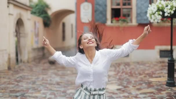 Young attractive woman walking on the street after rain look at camera spinning happy smile cute fashion water silhouette summer face female lonely stop close up — Stock Video