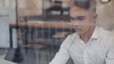 Bir dizüstü bilgisayarda çalışan bir kafede bir masada oturan bir ciddi genç iş adamı. Serbest, iletişim, Bilişim, başarılı insanlar