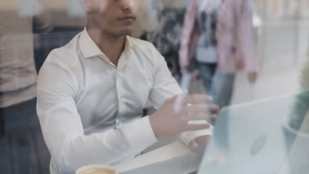 Joven hombre de negocios cansado sentado en una mesa en un café trabajando en un portátil. freelance, comunicación, IT, cansado concepto de hombre de negocios — Vídeo de stock