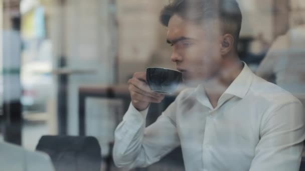Νεαρός επιχειρηματίας χρησιμοποιώντας φορητό υπολογιστή στο άνετο καφενείο και πίνει καφέ — Αρχείο Βίντεο