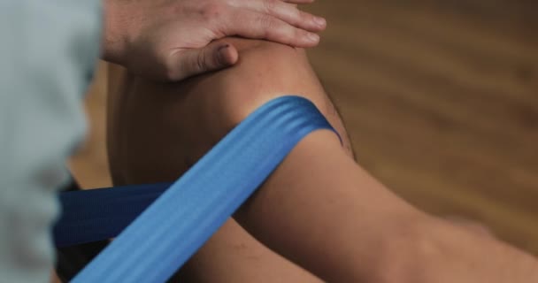 Fisioterapeuta haciendo tratamiento curativo en el brazo de los hombres con banda elástica azul. Tratamiento de la medicina alternativa y rehabilitación de pacientes — Vídeos de Stock