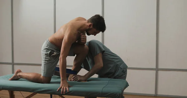 理学療法士男性患者での作業します。彼は病院のベッドの上の男性患者をストレッチ — ストック写真