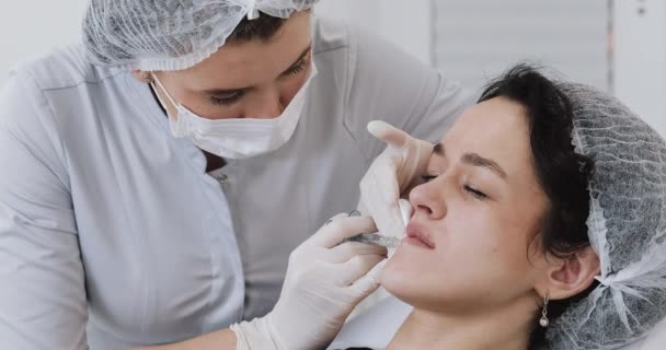 Läppförstoring. Läkarens kosmetolog gör läppförstoring av en vacker kvinna i en skönhetssalong. Kosmetisk skönhetsinjektion — Stockvideo