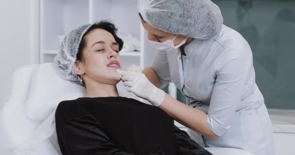 Aumento delle labbra. Il dottore cosmetologo fa la procedura di aumento di labbro di una bella donna in un salone di bellezza. Cosmetico concetto di iniezione di bellezza — Video Stock