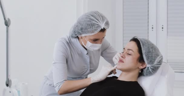 Zvětšení rtů. Lékař kosmetolog dělá zákrok zvětšení rtů krásné ženy v salonu krásy. Koncept kosmetické kosmetické injekce — Stock video