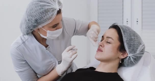 Aumento dos lábios. O médico cosmetologist faz procedimento de aumento labial de uma mulher bonita em um salão de beleza. Conceito de injeção de beleza cosmética — Vídeo de Stock