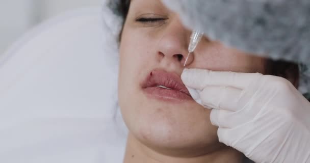 Powiększenie ust. Lekarz kosmetolog robi zabieg powiększania ust pięknej kobiety w salonie piękności. Kosmetyczna koncepcja wtrysku urody — Wideo stockowe