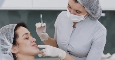 Güzel bir kadın güzellik uzmanı ziyaret ederken sandalyede oturan genç kadın. Kozmetik prosedürler için hazırlık. Dudak büyütme enjeksiyonları ile