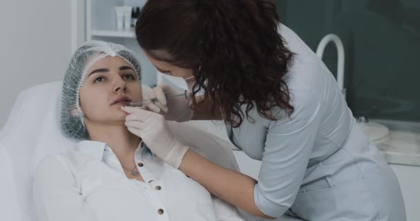 Lipvergroting. De arts cosmetoloog maakt lipvergroting procedure van een mooie vrouw in een schoonheidssalon. Cosmetische schoonheid injectie concept — Stockvideo