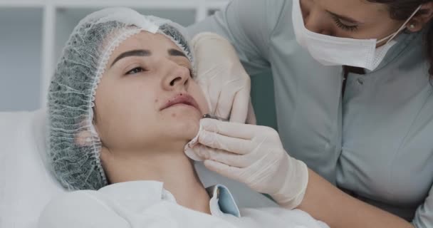 Aumento delle labbra. Il dottore cosmetologo fa la procedura di aumento di labbro di una bella donna in un salone di bellezza. Cosmetico concetto di iniezione di bellezza — Video Stock