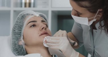 Dudak büyütme. Doktor kozmetik uzmanı güzellik salonunda güzel bir kadının dudak büyütme ameliyatını yapıyor. Kozmetik güzellik enjeksiyon konsepti