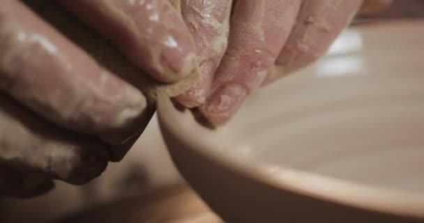 Поттер в гончарных колесах делает керамический продукт, используя свои руки и керамические инструменты. Закрывай. Ручная работа, мастерство. Белая глина — стоковое видео