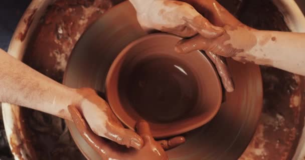 Handen van een paar vormen een pot klei op een Potters wiel. Een vrouwelijke hand helpt een Mans handen vorm een klei vorm. Top View. — Stockvideo