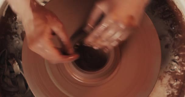 Potter makes pottery from clay close up. Making ceramic products from red clay. Twisted potters wheel. Woman hands making clay jug. Handmade, craft. Top view. — Stock Video