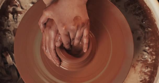 陶芸家は粘土から陶器をクローズアップします。赤い粘土からセラミック製品を作る。ねじれた陶器の車輪。粘土の水差しを作る男の手。手作り、工芸品。トップビュー. — ストック動画
