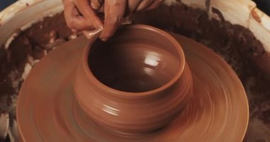Çömlekçi tekerleğinde çömlekçi, elleri ve çömlek aletleri kullanılarak seramik ürünü üreder. Yakından kapatın. El yapımı, zanaat. Kırmızı kil.