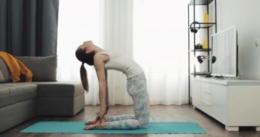 Genç kadın evde mat oturan ve bacak kasları germe yoga. Sağlıklı ve spor yaşam tarzı.