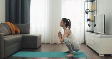 Evde yoga yapan genç bir kadın. Sağlıklı ve spor yaşam tarzı.