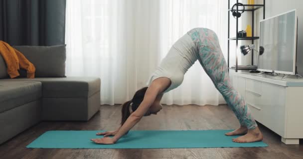 Une jeune femme qui fait de l'exercice à la maison. Fitness girl faire des exercices de yoga sur tapis. Mode de vie sain et sportif . — Video