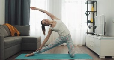 Evde yoga yapan genç bir kadın. Sağlıklı ve spor yaşam tarzı.