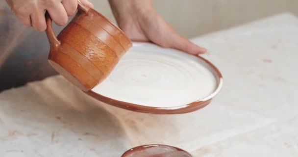 La glassa di vasaio esperta copre il piatto da argilla rossa. Chiudere. Processo. Laboratorio di ceramica . — Video Stock