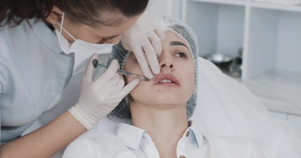 Powiększenie ust. Lekarz kosmetolog robi zabieg powiększania ust pięknej kobiety w salonie piękności. Kosmetyczna koncepcja wtrysku urody — Wideo stockowe