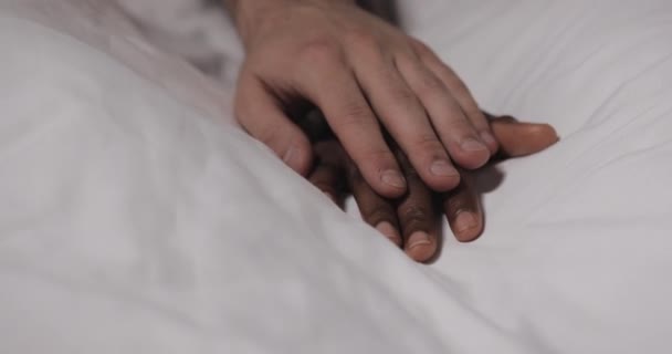 Multi-etnische paar in liefde liggend in bed samen. Close-up. Dames hand is liggend op een bed, Mans hand is strelen het en grijpen. — Stockvideo