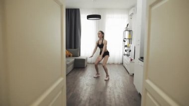 Genç bir kadın evde sağlıklı bir yaşam için spor yapıyor. Ağır çekim. Sağlıklı ve spor yaşam tarzı.
