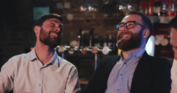 Lyckliga manliga vänner skrattar och pratar på bar eller pub. Handsome mens vilar i bar. — Stockvideo