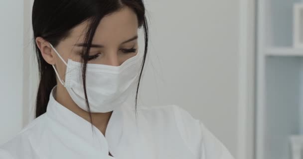Close-up van het gezicht van de vrouwelijke arts in het masker die de injectie-procedures maakt. Portret van de arts. — Stockvideo