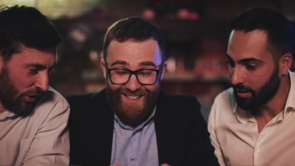 Tres viejos amigos viendo videos en smartphone y bebiendo cerveza de barril en el bar deportivo. Amigos riéndose y discutiendo las noticias en el pub de cerveza . — Vídeo de stock