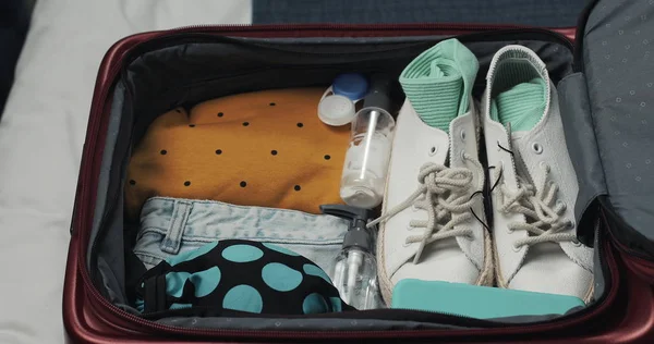 Mãos femininas desfazendo as malas para uma viagem na cama em casa. Preparativos de viagem . — Fotografia de Stock