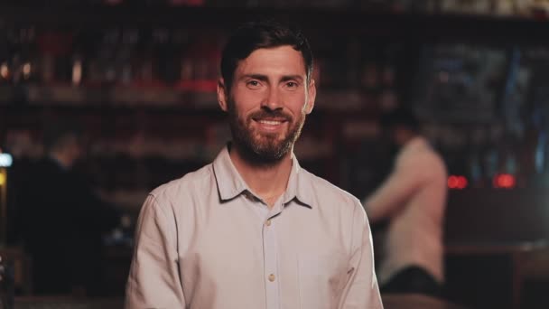 Портрет улыбающегося привлекательного мужчины, смотрящего в камеру в баре или пивном пабе. Концепция молодости, дружбы и отдыха . — стоковое видео