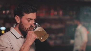 Çekici adam bira içme ve bir bar veya bira barda kamera bakarak Portresi. Gençlik, dostluk ve dinlenme kavramı.