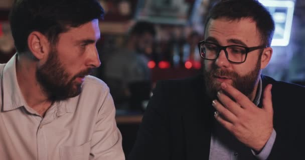 Deux vieux amis qui boivent de la bière pression et parlent au bar sportif. Amis assis au comptoir du bar, buvant de la bière et parlant dans un pub de bière . — Video