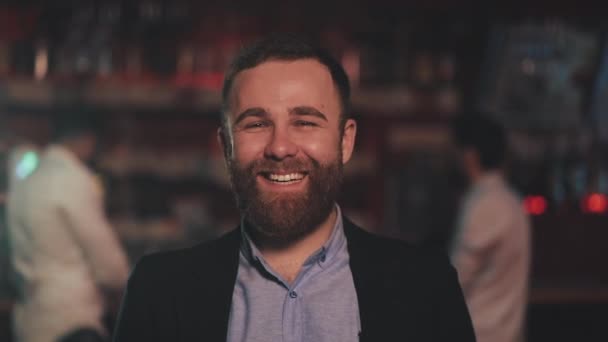 Retrato de homem atraente sorrindo olhando para a câmera em um bar ou pub de cerveja. Conceito de juventude, amizade e descanso . — Vídeo de Stock