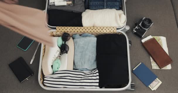 Von oben beim Kofferpacken. Frauenhände packen Sommersachen in einen Koffer. Roadtrip-Konzept. — Stockvideo