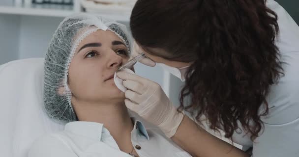 Увеличение губ. Врач-косметолог проводит процедуру наращивания губ красивой женщины в салоне красоты. Концепция инъекции косметической красоты — стоковое видео