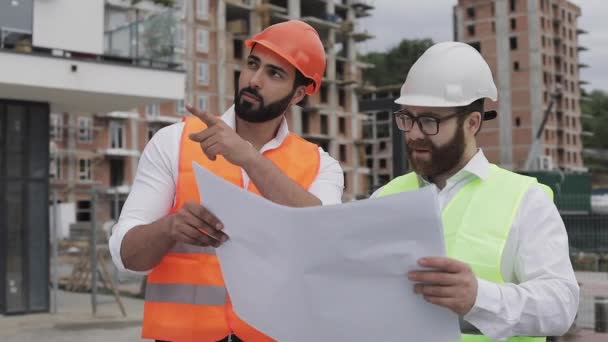 Arquitecto ingenieros expertos que hablan y analizan el plan de diseño de pie en el sitio de construcción. Profesiones, construcción, trabajadores, concepto de arquitecto. Movimiento lento . — Vídeos de Stock