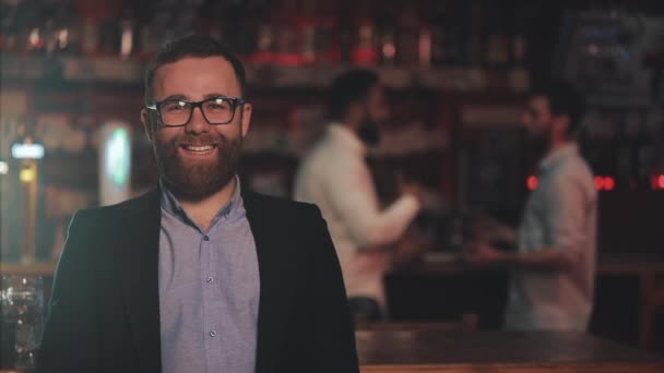 Portret uśmiechnięty atrakcyjny mężczyzna noszenia okularów patrząc na kamerę w barze lub pub piwny. Koncepcja młodzieży, przyjaźni i odpoczynku. — Wideo stockowe