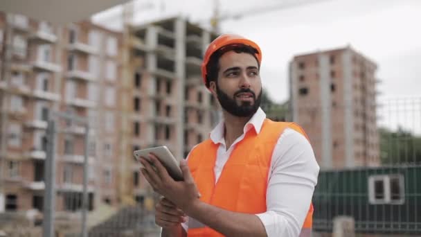 Architekt Mann geht mit Tablet auf die Baustelle und analysiert den Plan. Draußen, Zeitlupe. — Stockvideo