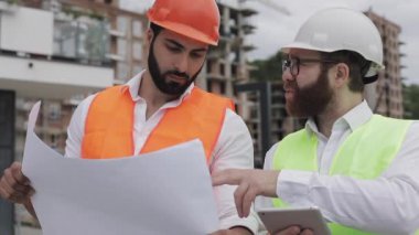 Bir konut kompleksi veya iş merkezi inşa. Bir tablet ve çizim analiz planlar inşaat üreticileri iş aktivitesi ile mühendis erkekler ekibi.
