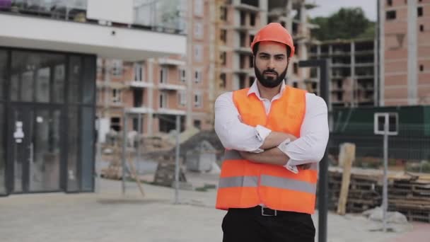 Портрет строителя на строительной площадке со скрещенными руками, смотрящего в камеру. Профессии, строительство, рабочие, архитектурная концепция . — стоковое видео