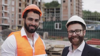 Mutlu inşaatçı ve işadamıportre inşaat alanı arka planda duran kameraya bakıyor. Meslekler, inşaat, işçi, mimar kavramı.